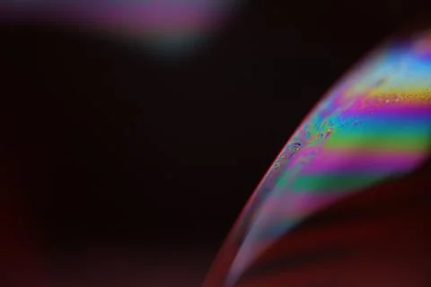 Bright rainbow reflection of liquid on black background Stock Photos