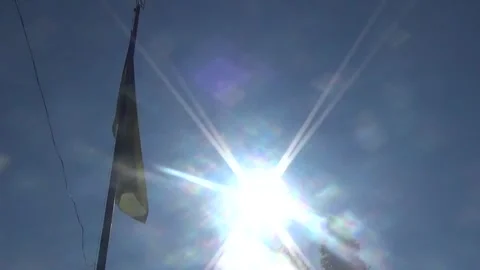 Bright rays of summer sun shine on the Ukrainian flag fluttering in the sky Stock-Footage 313218232
