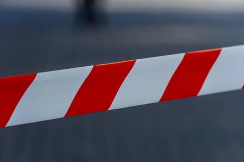 Bright red and white caution tape stretches across a city street, signaling.. 库存照片
