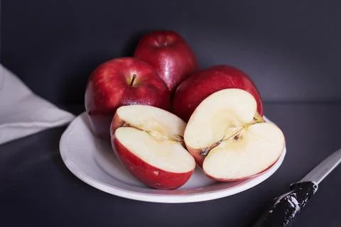 Bright red apples split in half in a white ceramic plate Stock Photos