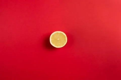Bright red background with half a lemon in the center of the image. Flat top  Stock Photos
