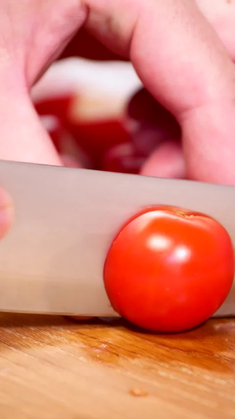 Bright red cherry tomatoes are halved with a knife, vertical 4k video Stock Footage 281966633