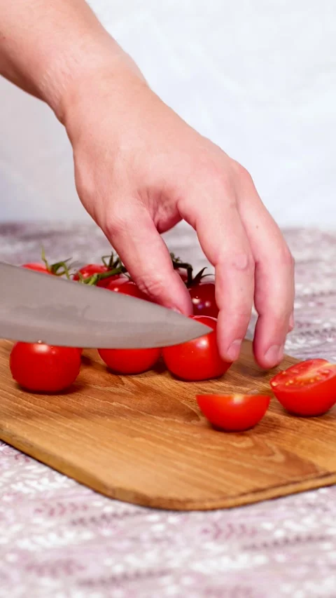 Bright red cherry tomatoes are halved with a knife, vertical 4k video Stock Footage 281967043
