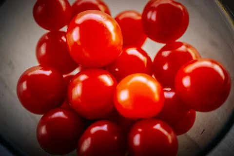 Bright red cherry tomatoes arranged in a bowl, showcasing their glossy surf.. Stock Photos