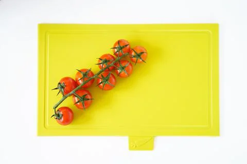 Bright red cherry tomatoes on white clean plastic cutting board with a kitchen Foto stock