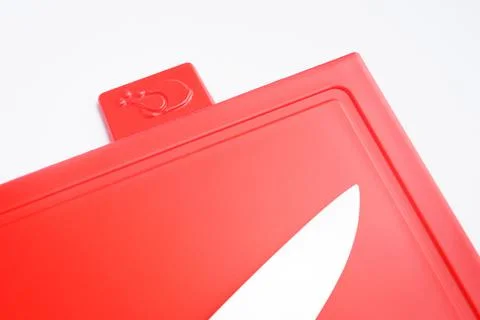 Bright red clean plastic cutting board with a kitchen knife on a white Stock Photos