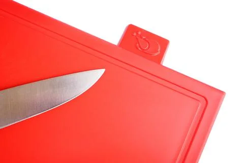 Bright red clean plastic cutting board with a kitchen knife on a white Stock Photos