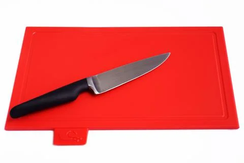 Bright red clean plastic cutting board with a kitchen knife on a white Stock Photos