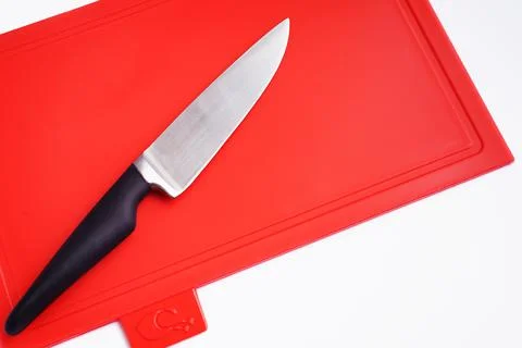 Bright red clean plastic cutting board with a kitchen knife on a white Stock Photos