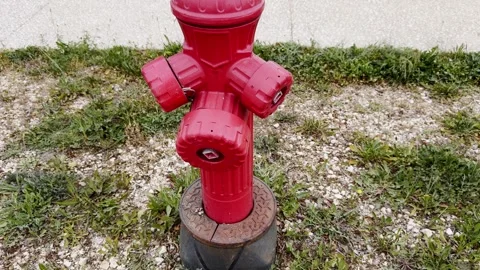 Bright red fire hydrant beside gravel, grass and a paved path, showing urban Stock Footage 338003059