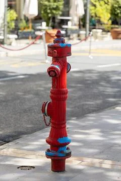Bright red fire hydrant stands prominently on sidewalk, showcasing vibrant .. Stock Photos