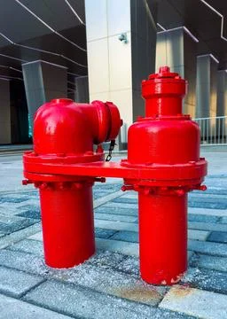 Bright red fire hydrant stands on pavement near a modern building in a city.. Fotos de archivo