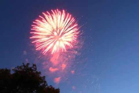 Bright red firework burst expanding in the twilight sky Фото