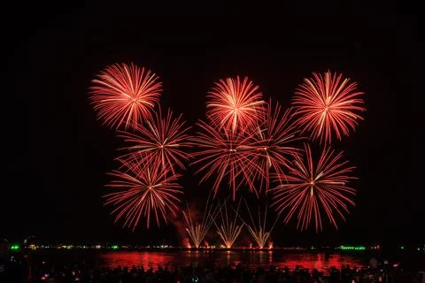 Bright Red Firework Bursts Illuminating Night Sky Over Water During Public .. Stock-Fotos