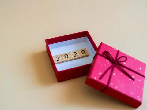 Bright red gift box containing wooden numbers for the year 2028 set against.. Stock Photos