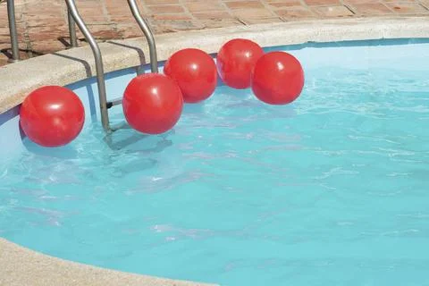 Bright red inflatable balls float on the surface of the laurel water in the p Foto stock