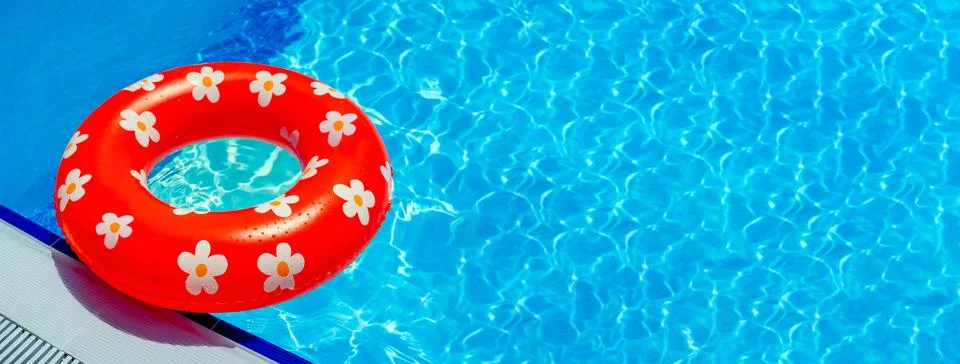 Bright red inflatable ring with a pattern of daisies on the edge of the pool Stock Photos