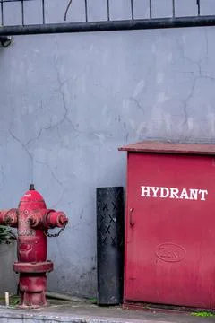 Bright Red isolated fire hydrant stand beside a grey roughly walls at the cor Stock Photos