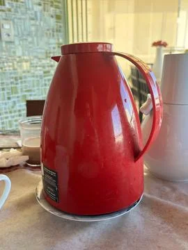 Bright red kettle on dining table Stock Photos