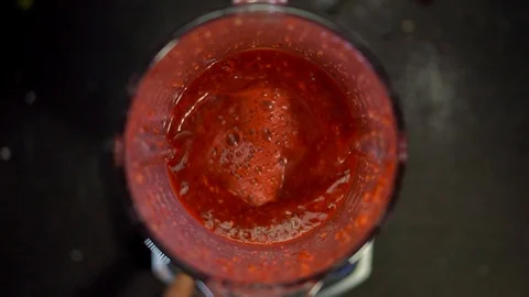 A bright red liquid in a lidless blender swirls and turns and stops with foam an Stock Footage 129823759