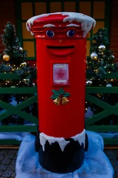 Bright red mailbox with snow decorations near holiday trees in winter season Stock Photos