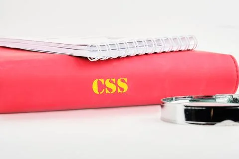 A bright red notebook labeled with CSS is placed next to a magnifying glass o 스톡 사진