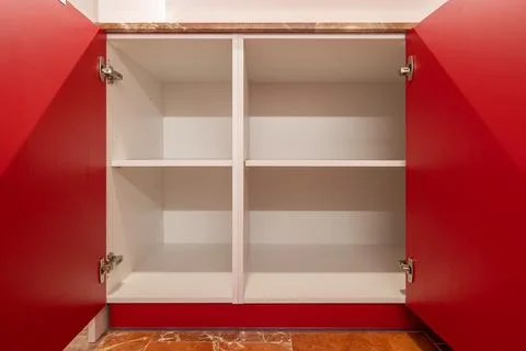 Bright red open cupboard with empty white shelves and a terracotta tiled floor Фото