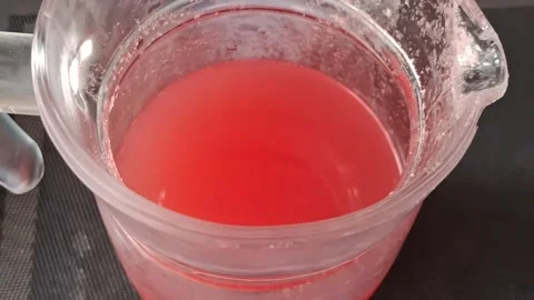 Bright red refreshing lemonade swirling inside a glass pitcher video footage Stock Footage 339248206