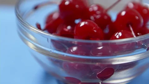 Bright red ripe cherries are placed on a white plate next to the glass of water Stock Footage 70964984