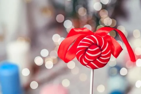Bright red round candy with a bow against the background of bokeh Stock Photos