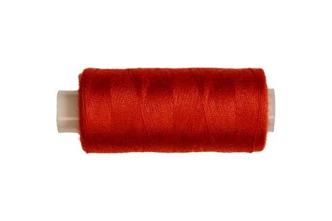 Bright red sewing thread spool on cylindrical plastic core surface Foto stock