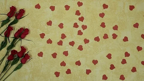 Bright red small hearts scatter on the table where the roses lie Stock Footage 102228448