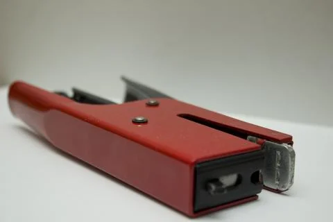 Bright red stapler resting on a clean surface, showcasing its sleek design .. Stock Photos