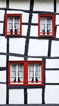 Bright red window frames on white and black timber framing facade 库存照片
