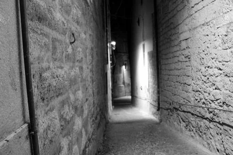 Bright reflections illuminate the cobblestone path in a narrow street in Riet Stock Photos