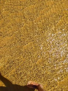 Bright ripples on the surface of the water. Golden sand beneath the brillian Stock Photos
