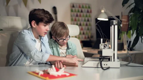 In bright room boys are talking to each other and controlling 3D printer work Stock Footage 335373216