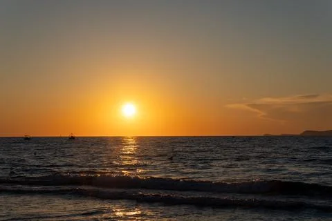 Bright round sun low over dark sea horizon at sunset Fotos Stock
