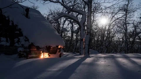 Bright shining moon lights the winter forest and a small wooden hut 4K timelapse Video stock 77146429