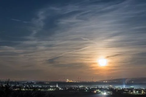 Bright shining moon on the sky with clouds and a city Stock Photos