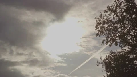 A bright shining sun breaking through dark clouds with a bird flying in Stock Footage 220764070