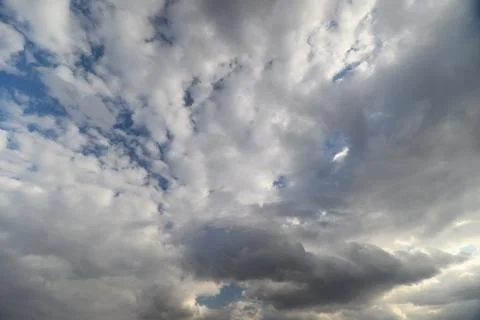 Bright sky with cloud patches. Cloudy sky illuminated by sunlight peeking throug Stock Photos