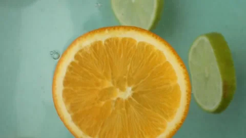 Bright slices of orange and lime dance lazily atop the water As the citrus Stock Footage 269999486