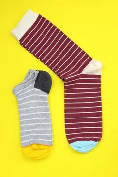 Bright socks of different sizes on a yellow background. Stock Photos