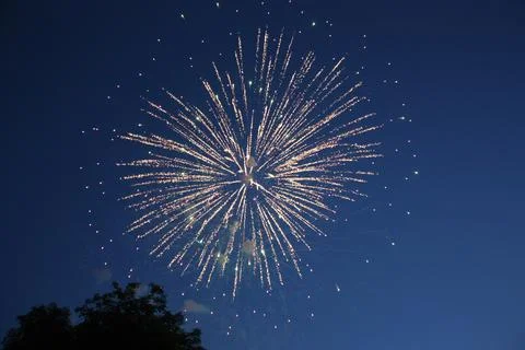Bright spherical firework burst expanding in the evening sky Фото