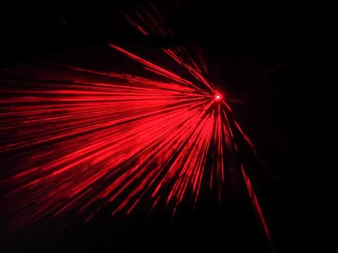 A bright spotlight projects red long beams in a dark space. Laser show. Blurred Stock Photos