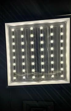 Bright square LED panel light fixture against dark ceiling, Stock Photos