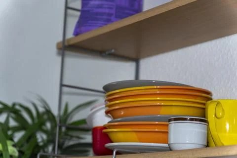A bright stack of dishes on an open kitchen shelf. Stock Photos