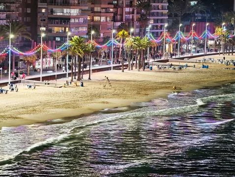 Bright String Lighting Reflecting On Moist Sands Amidst Bustling Seaside Stock Photos