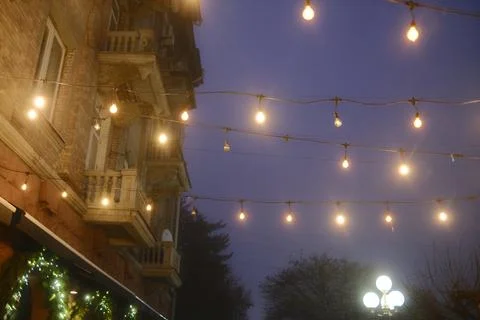 Bright string lights illuminating an old city street at night Stock Photos